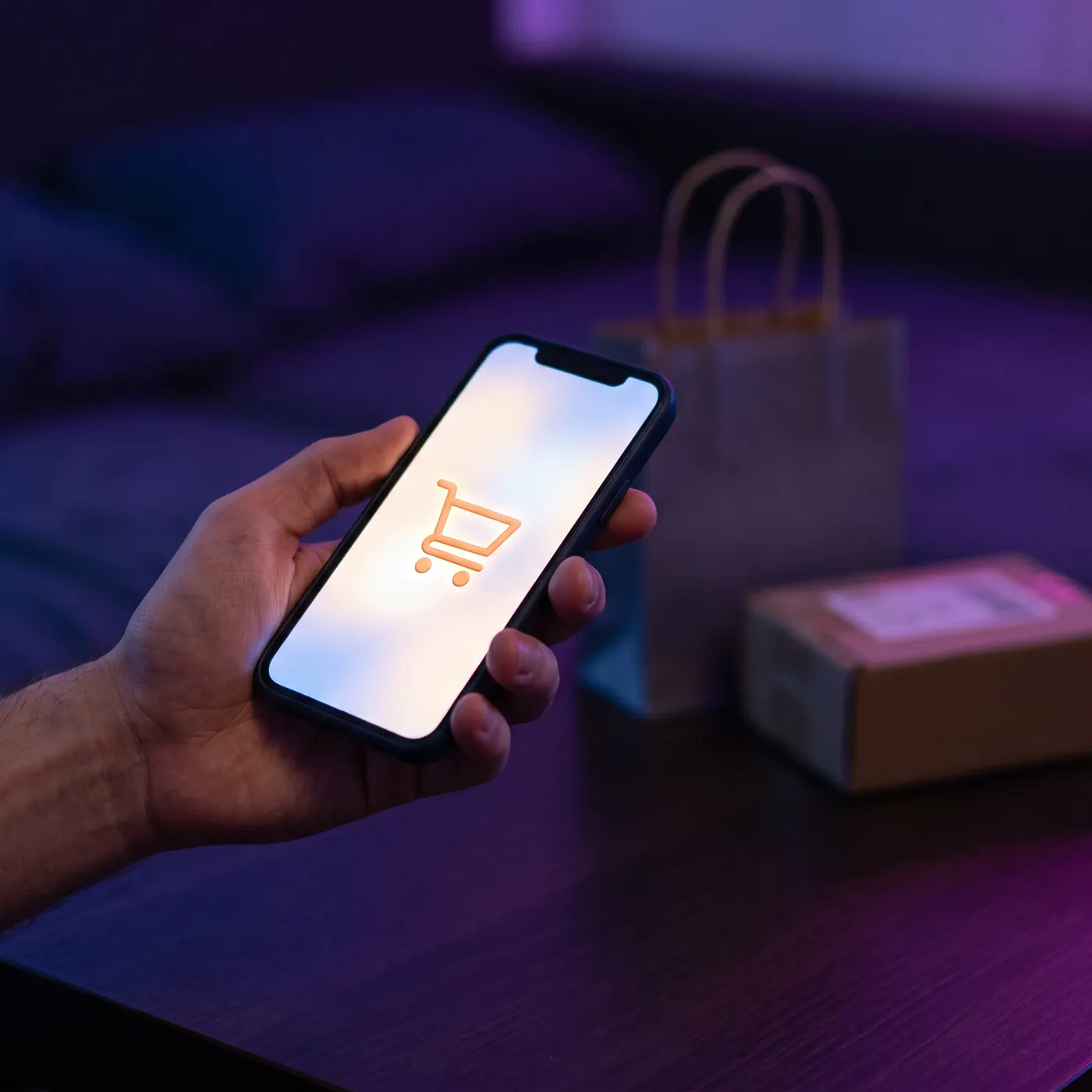 Persona sosteniendo un celular con el ícono de carrito de compra de una tienda online